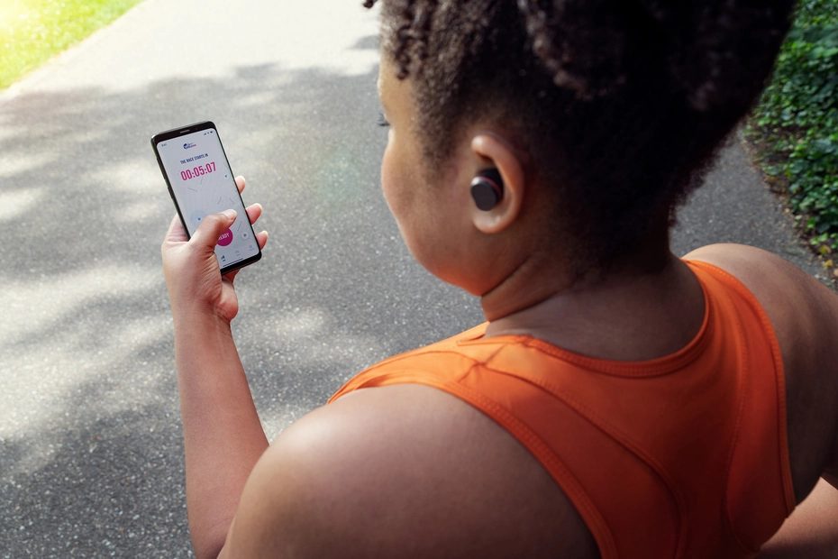 Philips SportsヘッドフォンとWings for Life World Runアプリを使用する女性